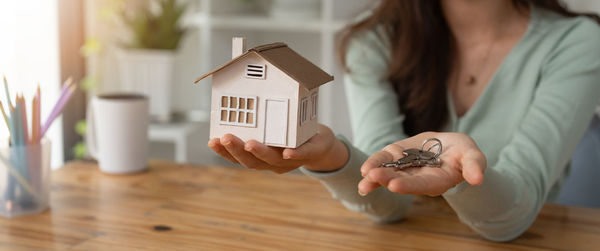 Midsection of woman holding model house