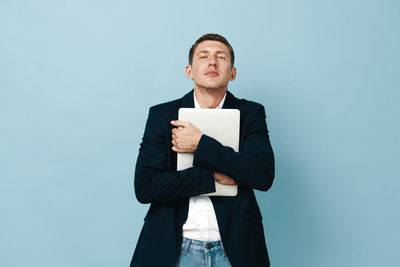 Portrait of young businessman standing against blue background