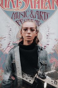 Portrait of man wearing sunglasses standing against graffiti