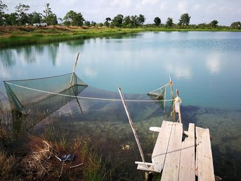 Wooden posts in lake against sky