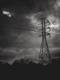 Low angle view of electricity pylon against cloudy sky