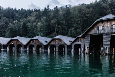 House by lake and buildings against sky