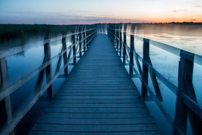 View of wooden bridge over calm lake