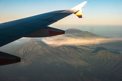 Airplane flying over mountains against sky