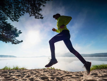 Silhouette of a sportsman running along the beach of the sea during an amazing misty daybreak