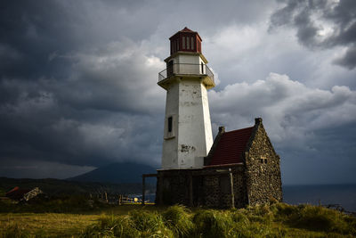 Lighthouse by building against sky
