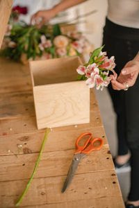 Midsection of woman holding flowers on table