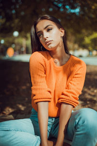 Young woman looking away while sitting outdoors