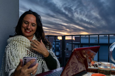 Young woman using mobile phone while sitting on table