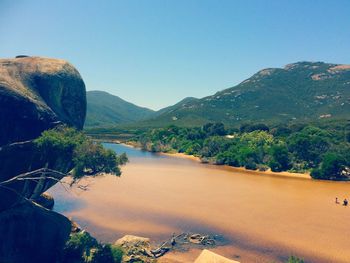 Scenic view of river by mountains against clear sky