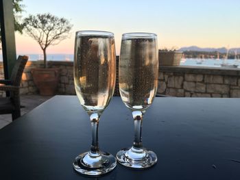 Close-up of champagne flutes on table against clear sky during sunset