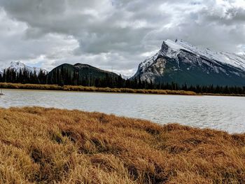 Scenic view of lake by snowcapped mountains against sky