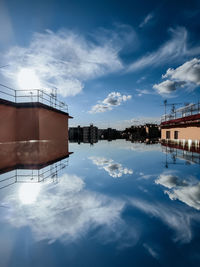 Factory by lake against sky