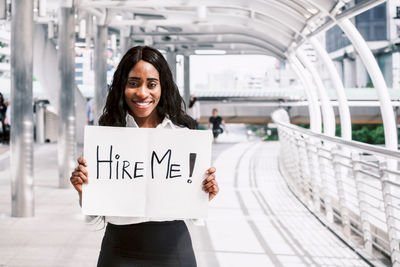 Businesswoman holding placard while standing in covered footbridge