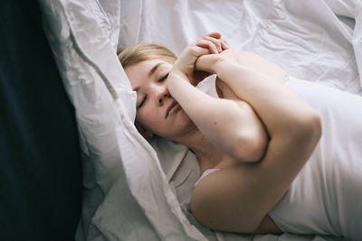 Midsection of young woman holding hands on bed