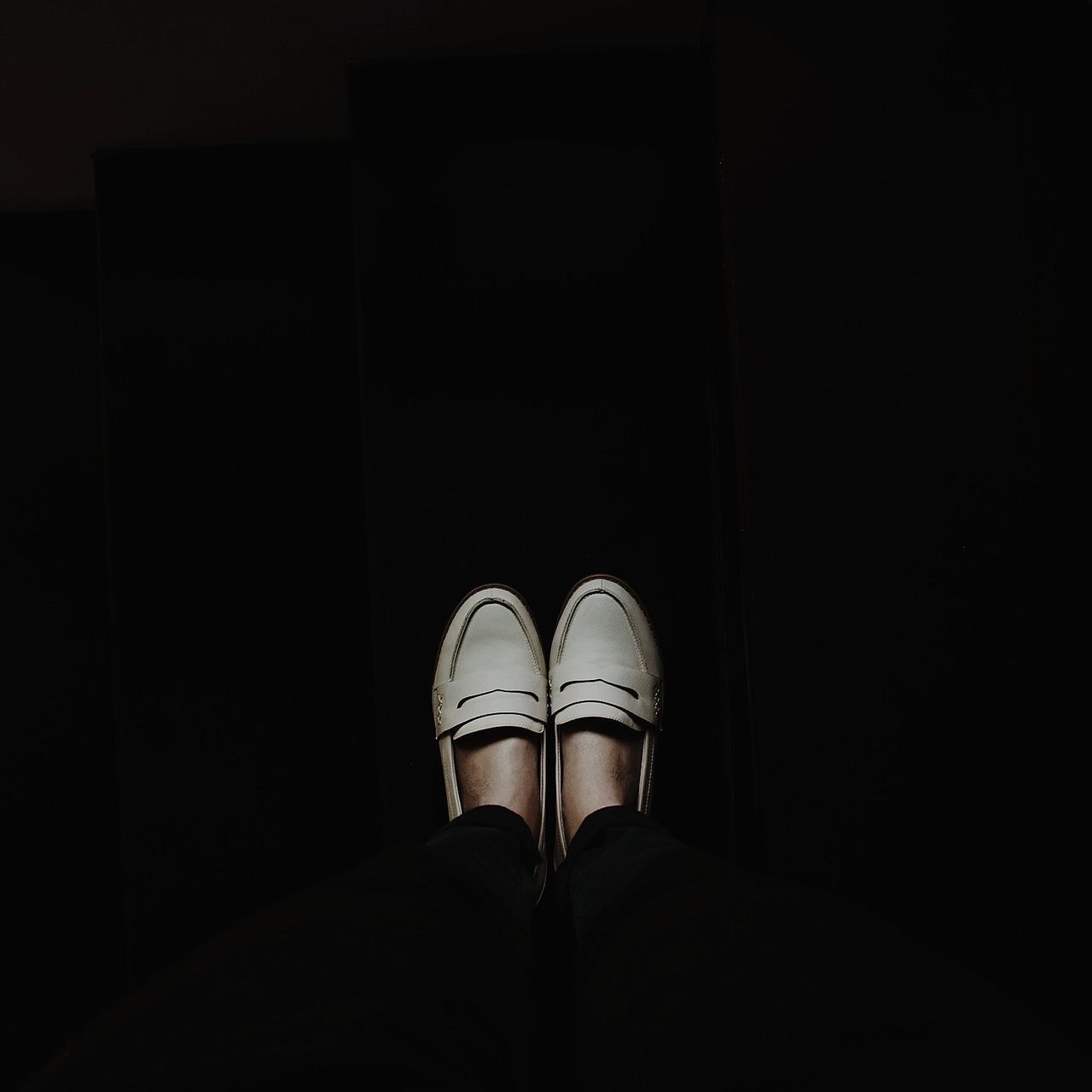 low section, person, shoe, indoors, personal perspective, standing, copy space, footwear, dark, night, men, lifestyles, illuminated, human foot, unrecognizable person, part of, high angle view