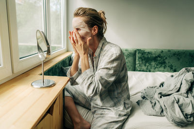 Young woman using mobile phone while lying on bed at home