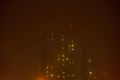 Defocused image of illuminated buildings against sky at night