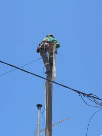 Low angle view of electricity pylon against clear blue sky