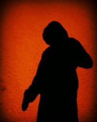 Rear view of silhouette boy standing against wall