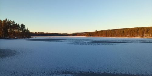 Scenic view of lake against clear sky during winter