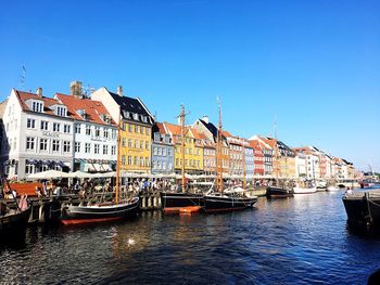 Sailboats moored on canal by buildings against sky