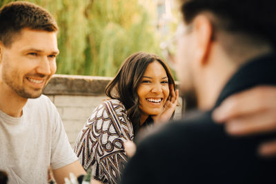 Young female smiling while sitting with friends at social gathering