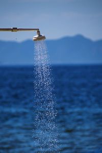 Water flowing from shower by sea against sky