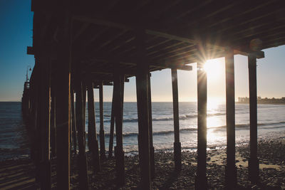 Silhouette pier over sea against sky during sunset