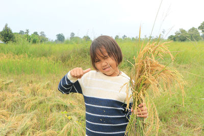 Asian children smiling woman farmer holding rice plant at rice field.