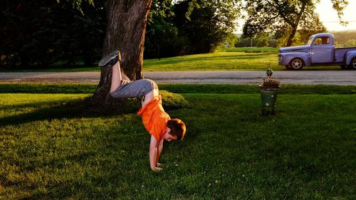 Boy doing handstand on grassy field at park