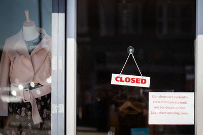 Close-up of information sign hanging on glass window at store