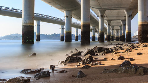 Scenic view of beach by bridge against sky