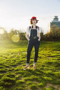 Full length portrait of confident woman standing against clear sky in park