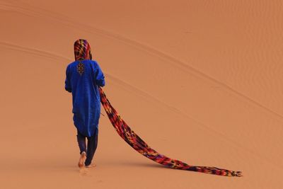 Full length of young woman walking on sand dune in desert
