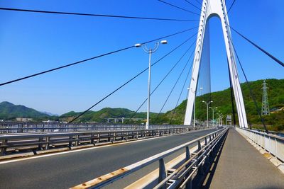 Bridge over road against blue sky in city