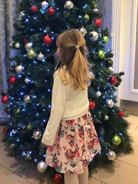 Rear view of girl with christmas tree at home