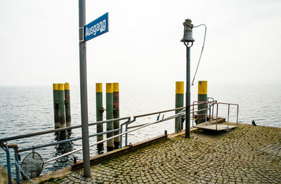 Information sign on street by sea against clear sky