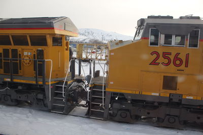 Vehicles on road against sky during winter