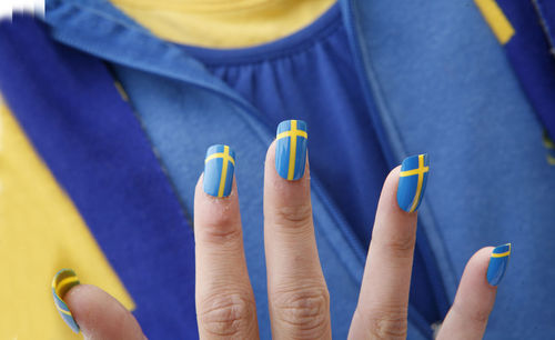 Close-up of swedish flag represented on woman nails