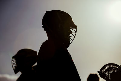 Silhouette man wearing sports clothing and helmet standing against sky during sunset