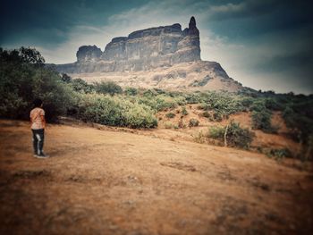 Man standing on rock with mountain in background