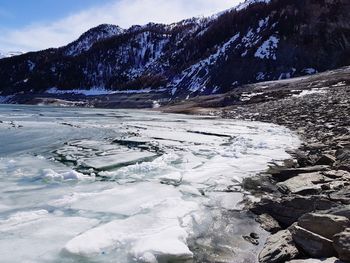 Scenic view of frozen lake against mountains and sky during winter