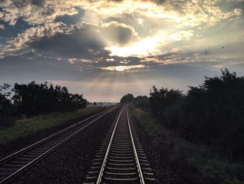 Railroad track against cloudy sky at sunset