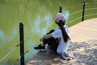 Rear view of woman sitting by lake