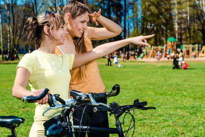 Smiling friends looking away while standing at park