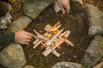 High angle view of man by fire pit at campsite in forest