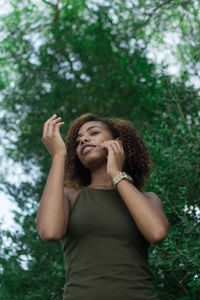 Low angle view of woman with curly hair against trees