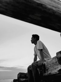 Low angle view of young man looking away against sky