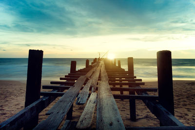 Wooden pier on sea against sky during sunset